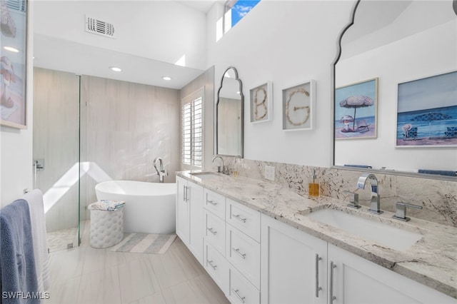 bathroom with double vanity, a freestanding bath, visible vents, and a sink