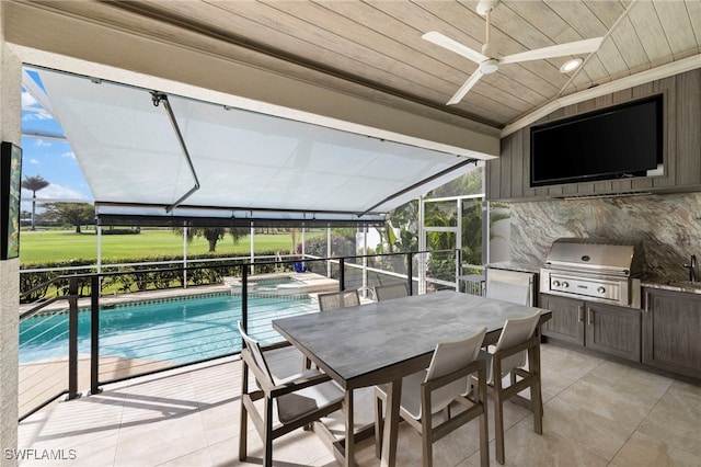 view of pool featuring a patio, area for grilling, an outdoor kitchen, a ceiling fan, and a lanai