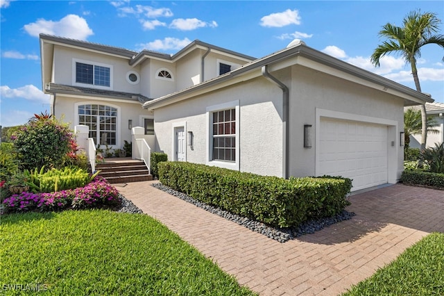 traditional-style house featuring a garage, decorative driveway, and stucco siding