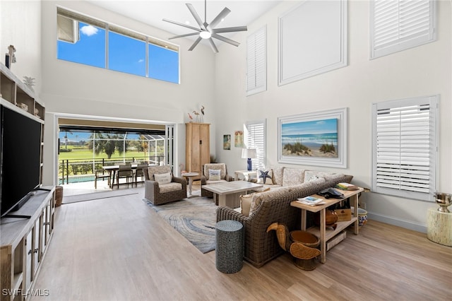 living room featuring a sunroom, ceiling fan, baseboards, and wood finished floors