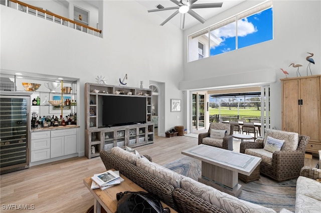 living room featuring a ceiling fan, light wood-type flooring, a healthy amount of sunlight, and a dry bar