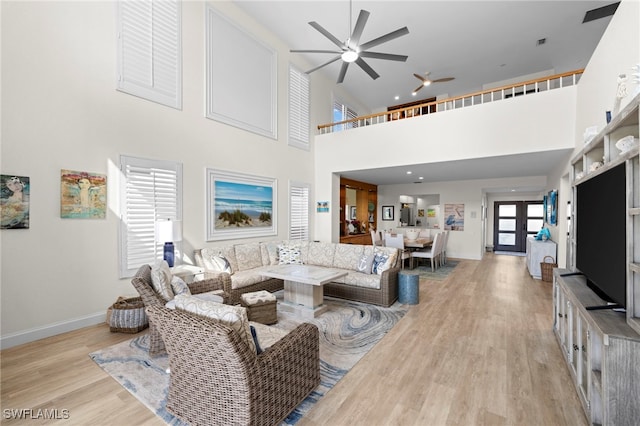 living area with light wood-style flooring, baseboards, a ceiling fan, and french doors