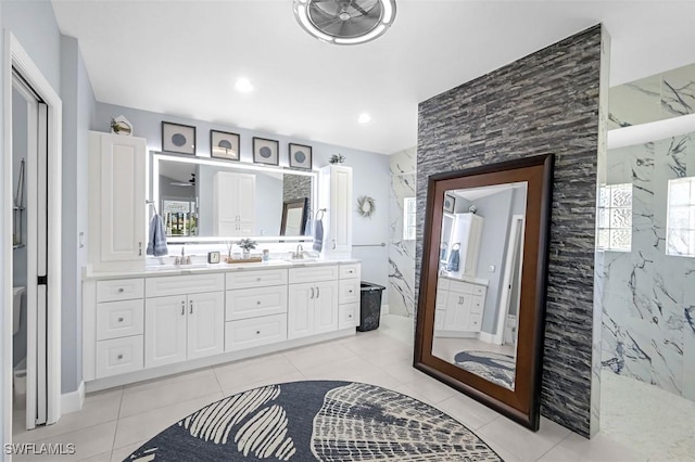 full bathroom featuring double vanity, a marble finish shower, a sink, and tile patterned floors