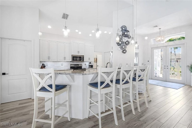 2345 SW 28th Ter, Cape Coral, FL 33914 - kitchen with appliances with stainless steel finishes, light wood-type flooring, white cabinetry, tasteful backsplash, and recessed lighting