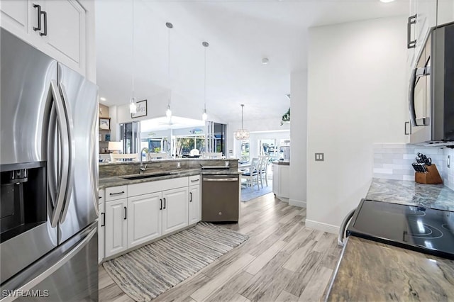 kitchen with backsplash, appliances with stainless steel finishes, white cabinetry, a sink, and light wood-type flooring