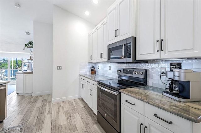 kitchen featuring stainless steel appliances, visible vents, decorative backsplash, and dark stone countertops