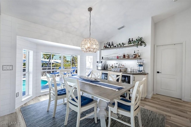 dining area featuring light wood-type flooring, vaulted ceiling, visible vents, and a chandelier