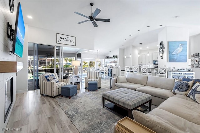 living area featuring light wood-style floors, ceiling fan, and a fireplace