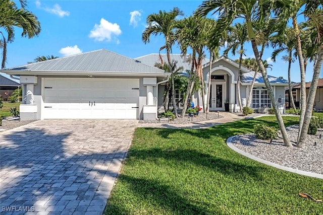 ranch-style house with decorative driveway, french doors, stucco siding, an attached garage, and a front lawn