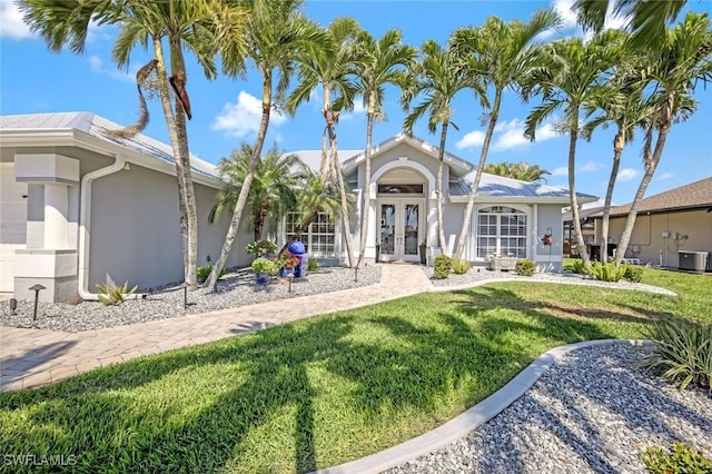 view of front of home with cooling unit, french doors, a front yard, and stucco siding