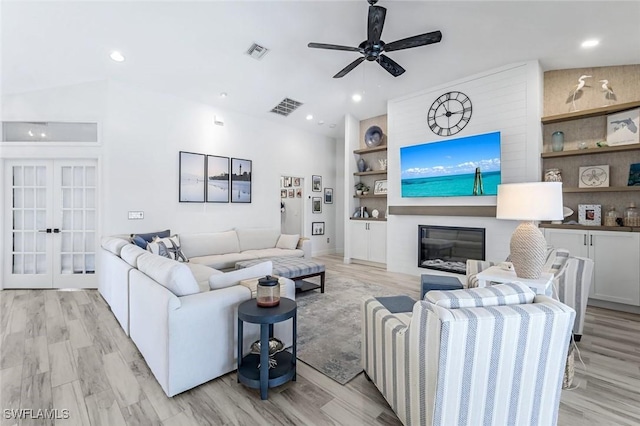 living area with built in features, french doors, a fireplace, light wood finished floors, and visible vents