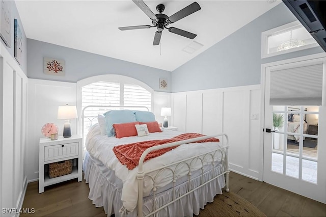 bedroom featuring a decorative wall, vaulted ceiling, dark wood-type flooring, and wainscoting