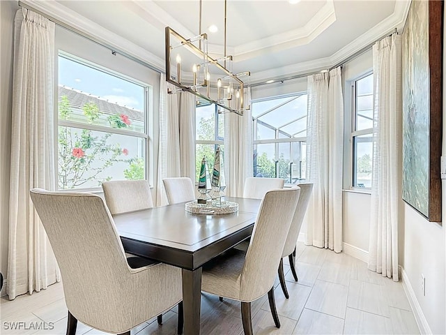 dining space with a chandelier, a tray ceiling, ornamental molding, and baseboards