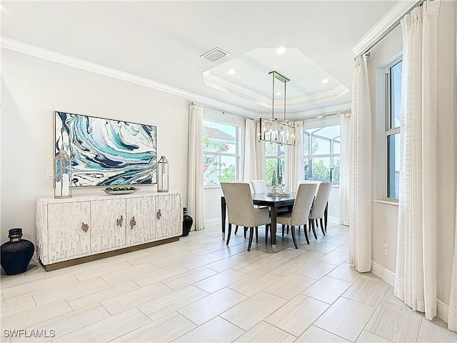 dining room featuring a notable chandelier, visible vents, baseboards, a tray ceiling, and crown molding