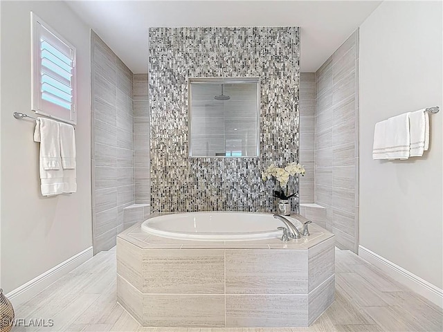 full bathroom featuring a garden tub, a tile shower, and baseboards