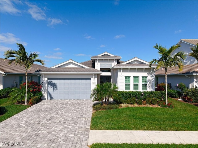 view of front of property with a garage, a tile roof, decorative driveway, and a front yard