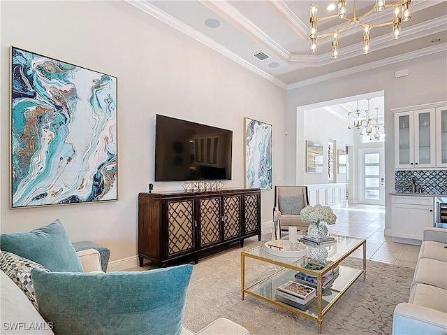 living room featuring a tray ceiling, light tile patterned floors, visible vents, ornamental molding, and a chandelier