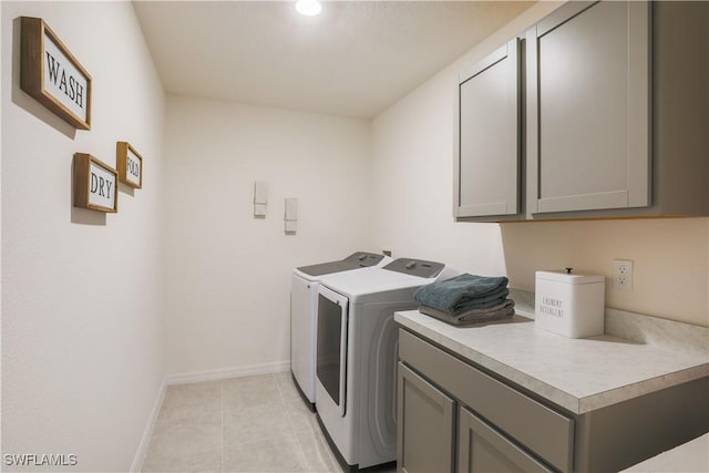 clothes washing area with separate washer and dryer, light tile patterned flooring, cabinet space, and baseboards