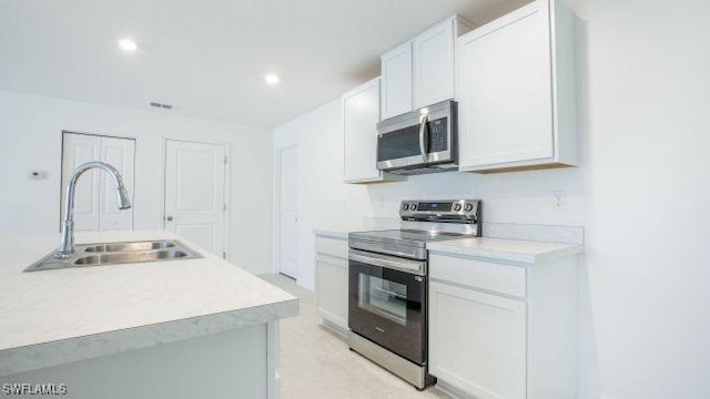 kitchen featuring light countertops, appliances with stainless steel finishes, a sink, and white cabinets