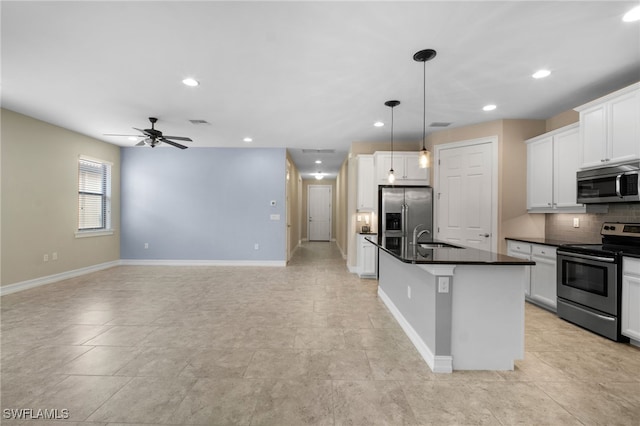 kitchen with a center island with sink, stainless steel appliances, dark countertops, tasteful backsplash, and a sink