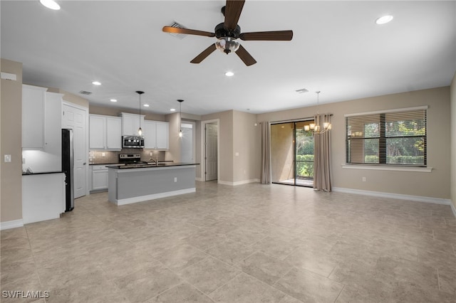 kitchen with a center island with sink, stainless steel appliances, dark countertops, open floor plan, and white cabinets