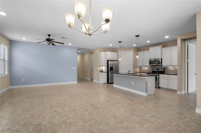 kitchen featuring ceiling fan with notable chandelier, a sink, open floor plan, appliances with stainless steel finishes, and dark countertops