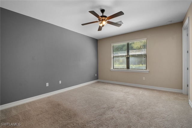 empty room featuring a ceiling fan, light carpet, visible vents, and baseboards