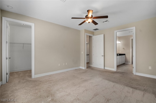 unfurnished bedroom with carpet, a walk in closet, visible vents, and baseboards