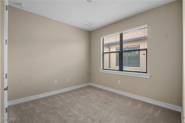 spare room featuring carpet flooring, visible vents, and baseboards