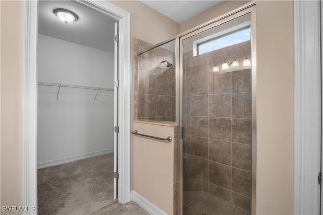 full bath with a stall shower, a spacious closet, and baseboards