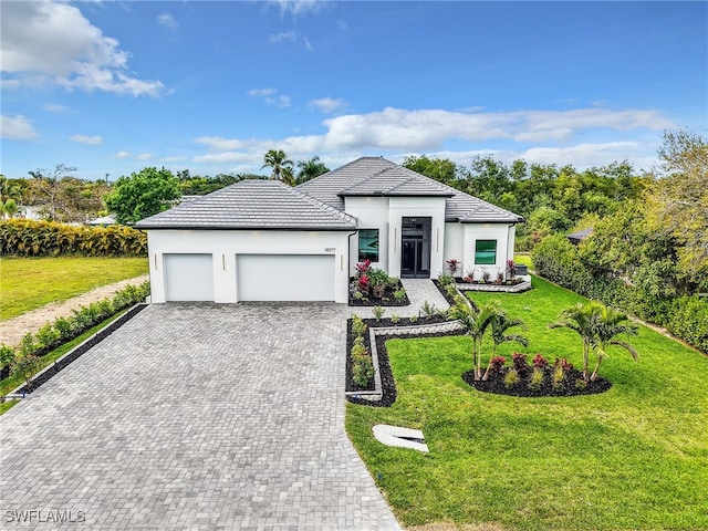 view of front of home with an attached garage, decorative driveway, a front yard, and stucco siding