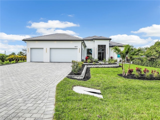 prairie-style house featuring a garage, a front yard, decorative driveway, and stucco siding