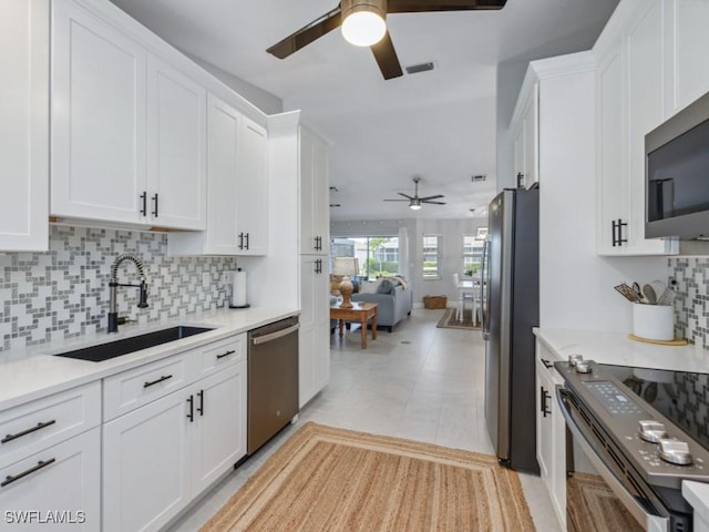 kitchen with stainless steel appliances, light countertops, visible vents, white cabinetry, and a sink