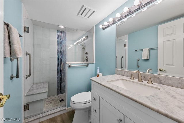 full bathroom with visible vents, toilet, wood finished floors, a shower stall, and vanity