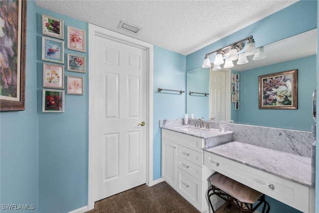 bathroom featuring visible vents, a textured ceiling, vanity, and baseboards