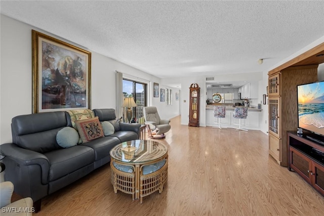 living room featuring visible vents, a textured ceiling, and light wood-style flooring