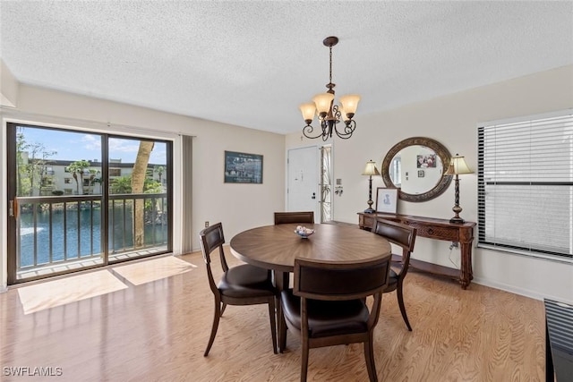 dining room featuring a notable chandelier, a textured ceiling, light wood-type flooring, and baseboards