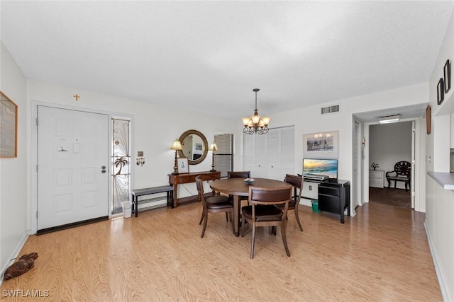 dining room featuring a notable chandelier, light wood-style floors, visible vents, and baseboards