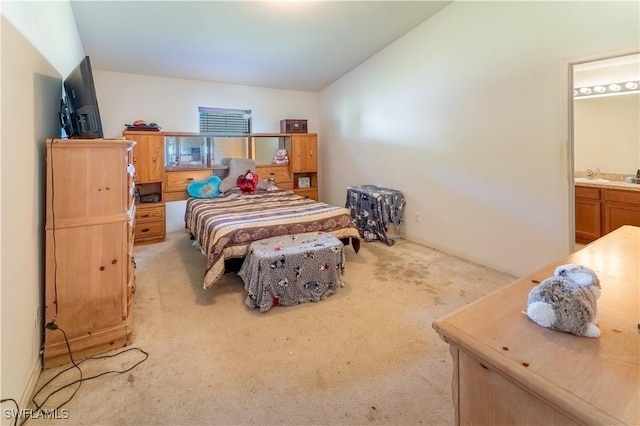 bedroom with light carpet, vaulted ceiling, a sink, and connected bathroom