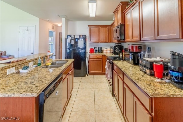 kitchen with light tile patterned floors, a kitchen island with sink, a sink, light stone countertops, and black appliances