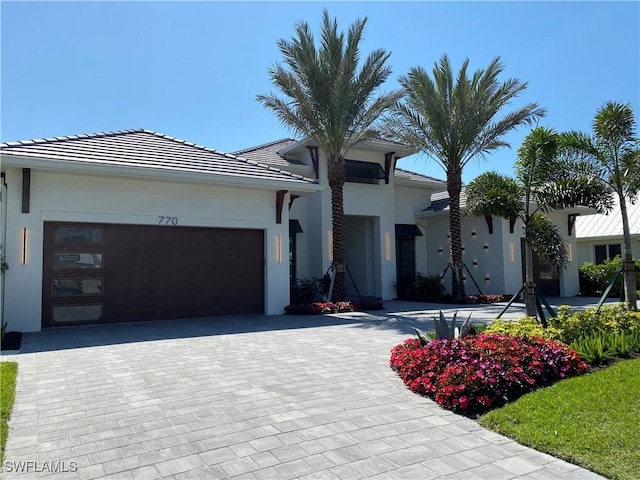 view of front of property featuring decorative driveway, an attached garage, and stucco siding