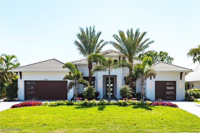 view of front of home featuring concrete driveway, french doors, an attached garage, and a front lawn