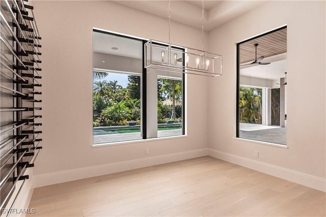 spare room with baseboards, wood finished floors, and a healthy amount of sunlight