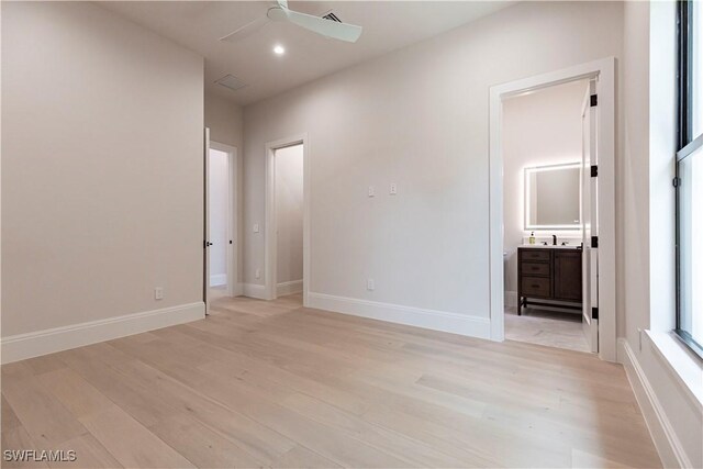 unfurnished bedroom featuring light wood finished floors, baseboards, and ensuite bathroom
