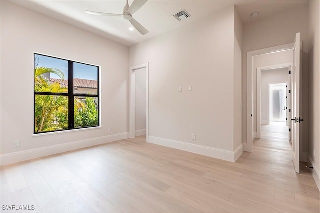 empty room featuring light wood-type flooring, ceiling fan, baseboards, and visible vents