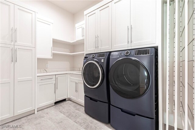 770 Port Side Dr, Naples, FL 34103 - laundry area with cabinet space, washer and clothes dryer, and light wood-type flooring