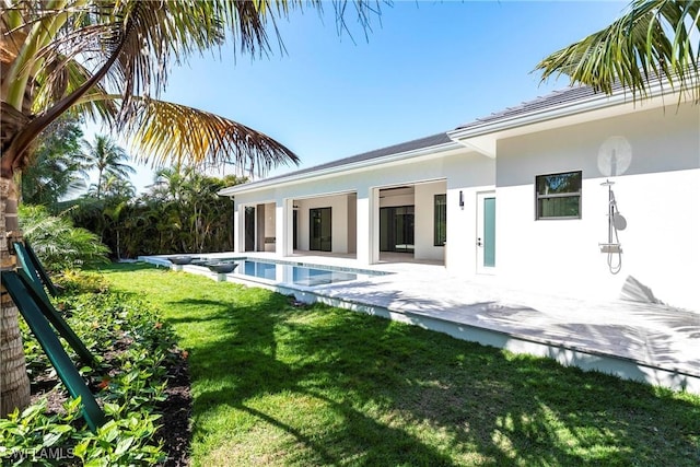 rear view of house with a yard, a patio, stucco siding, and an outdoor pool