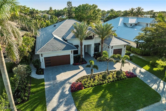 view of front of house featuring a front yard, a tiled roof, decorative driveway, and a garage