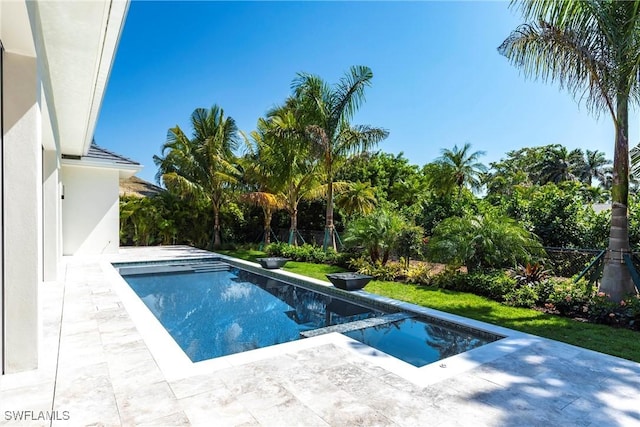 pool with a patio area, fence, and an in ground hot tub