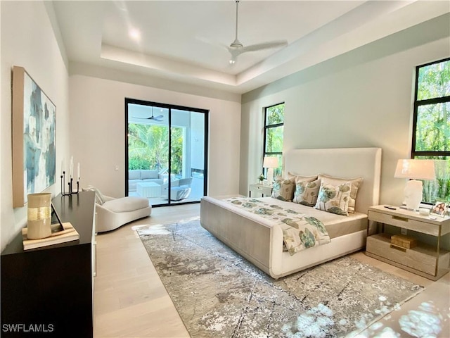 770 Port Side Dr, Naples, FL 34103 - bedroom featuring access to outside, multiple windows, a tray ceiling, and wood finished floors